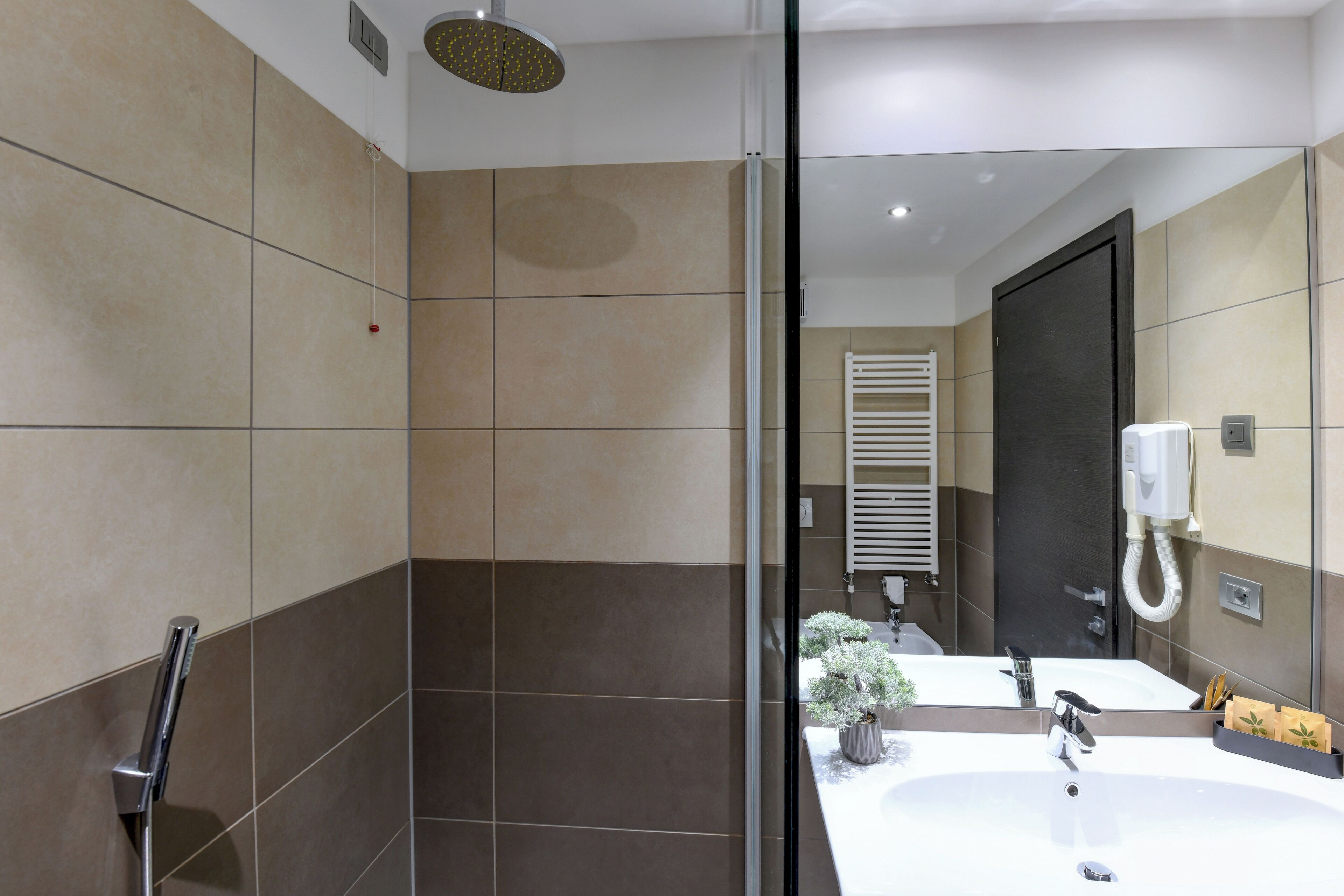 Une salle de bain moderne avec une douche à parois de verre, un lavabo blanc et un miroir.
