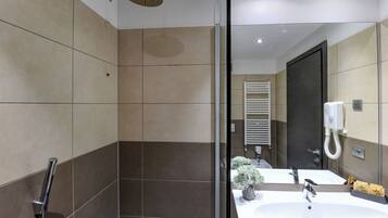 Une salle de bain moderne avec une douche à parois de verre, un lavabo blanc et un miroir.