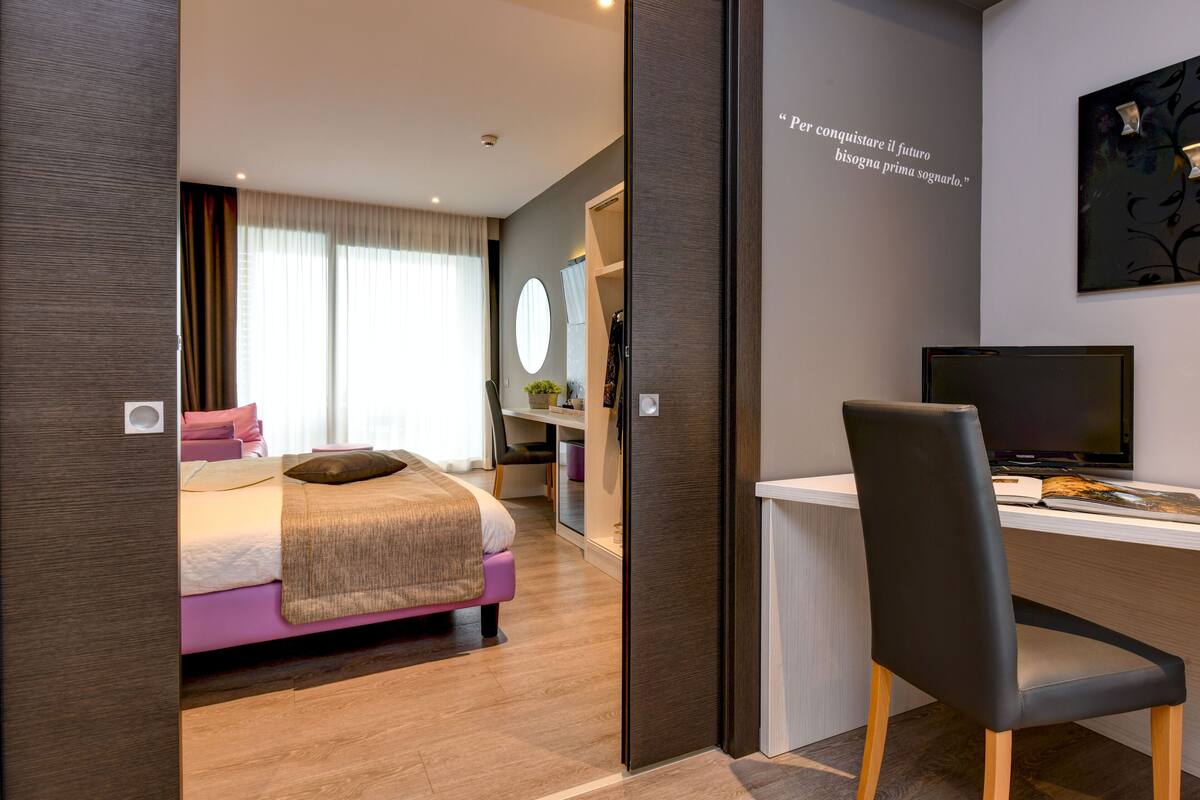 Una habitación de hotel moderna con cama, escritorio y silla.