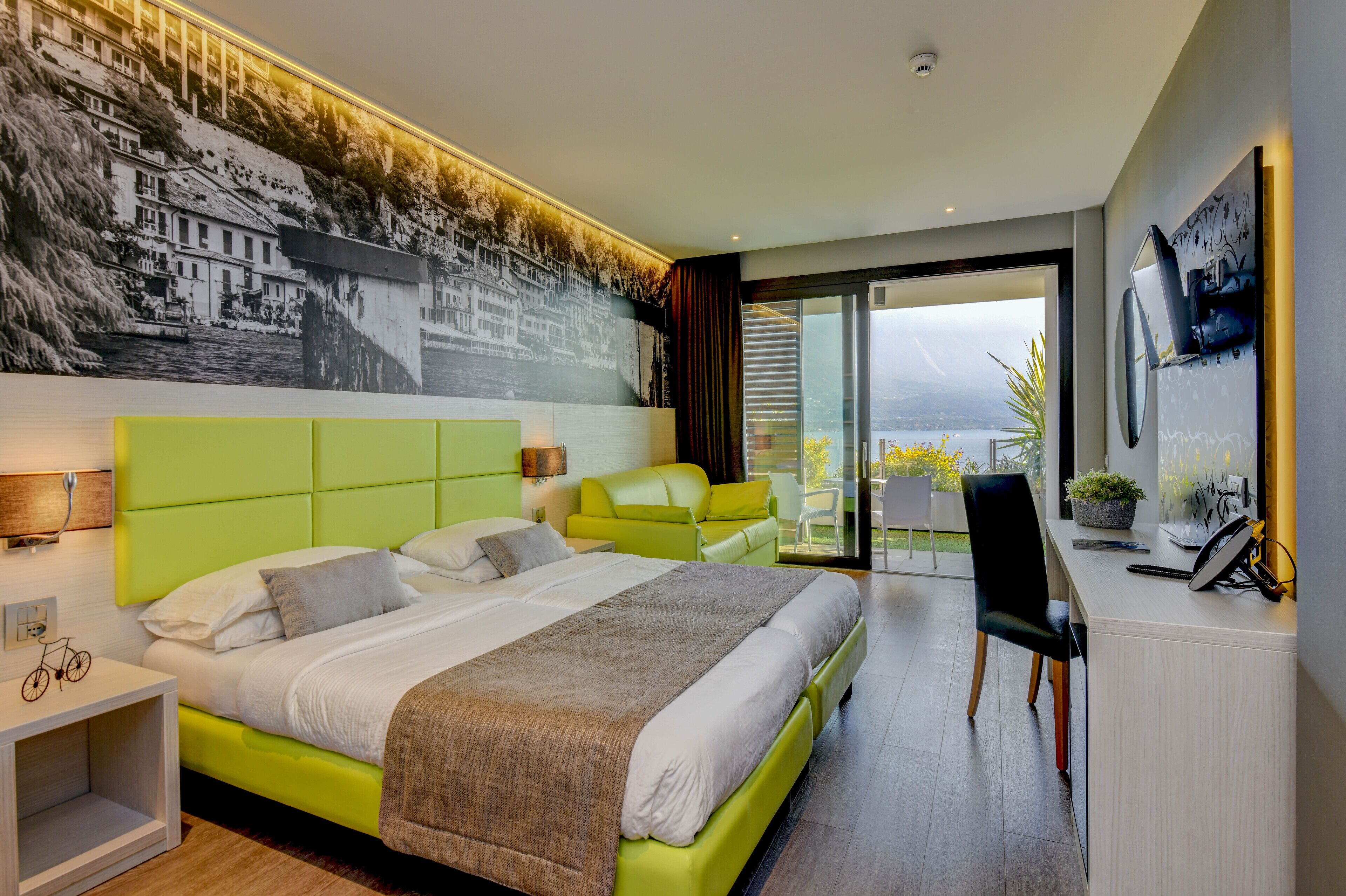 Una moderna camera d'hotel con un letto grande, una scrivania e un balcone con vista.