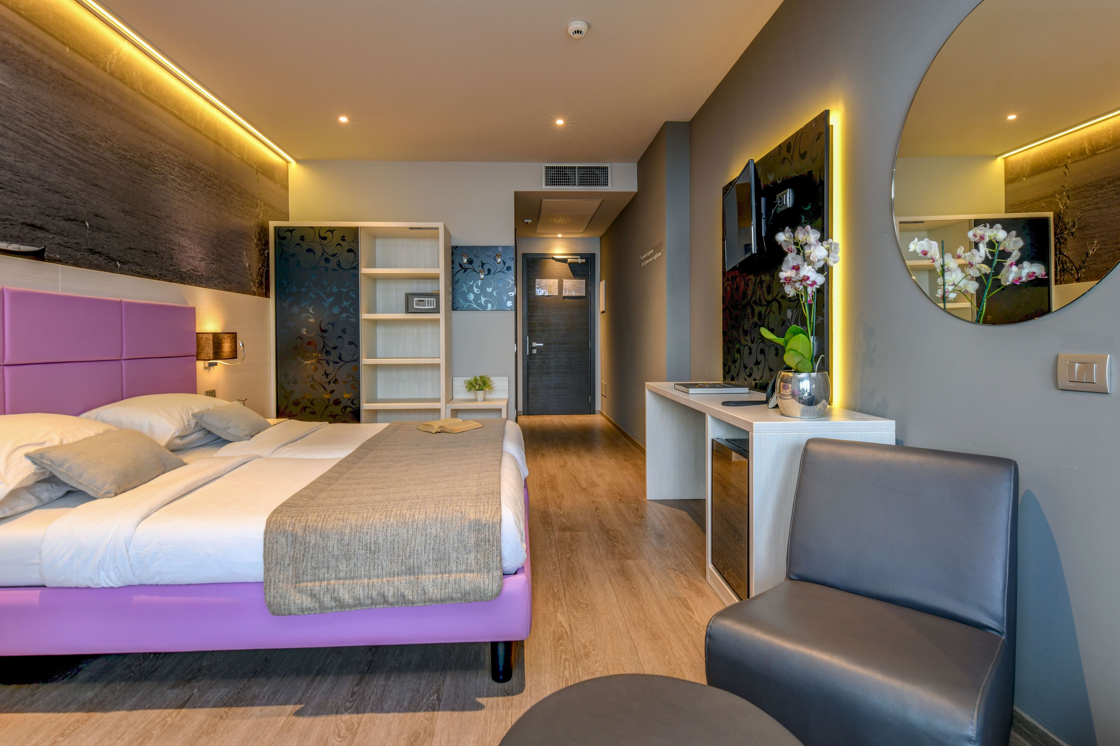 A modern bedroom with a bed, bedside table, and a desk with a chair.