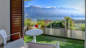Ein Balkon mit Blick auf Berge und einen See, mit einem Tisch, zwei Gläsern und einer Pflanze.