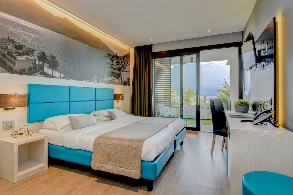 Una habitación de hotel moderna con una cama grande, un escritorio y vistas a las montañas.
