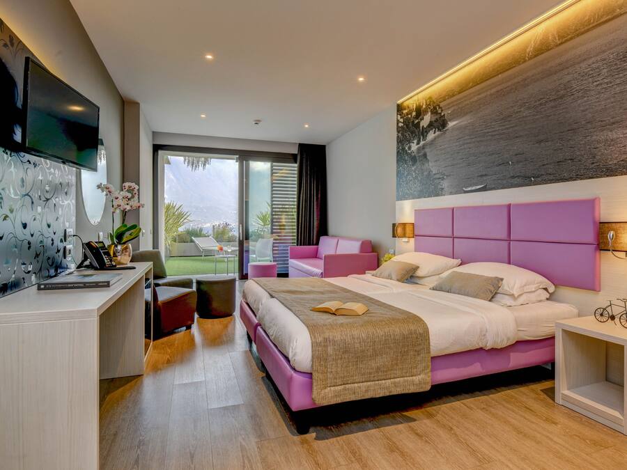 Quarto moderno com uma cama grande, uma escrivaninha e uma televisão.