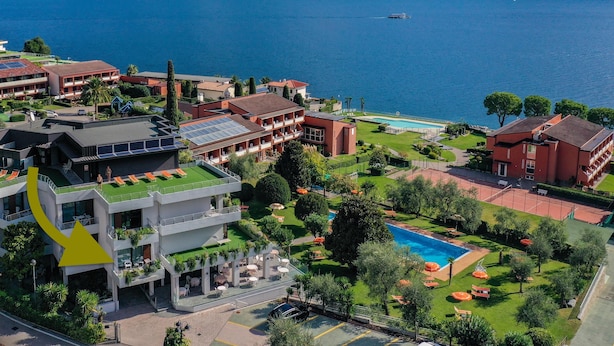 Ein Hotel mit mehreren Gebäuden, einem Schwimmbad und Blick auf einen See.