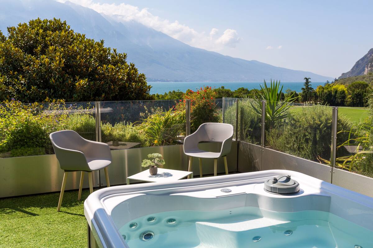 Un balcón con jacuzzi, dos sillas y una mesita con planta en maceta.