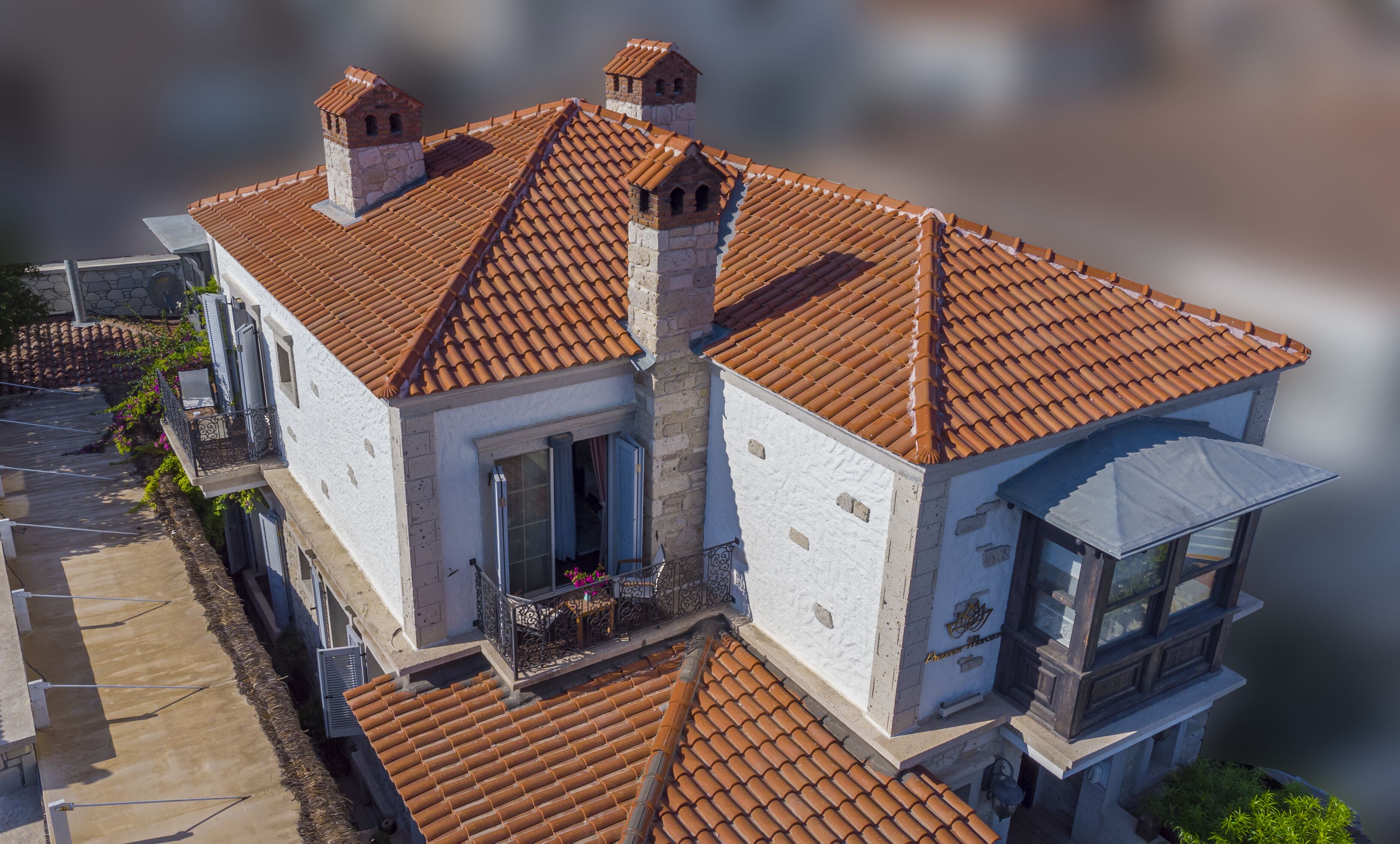 A two-story building with a tiled roof, a balcony with railings, and a small tower-like structure on the roof.