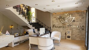 A modern interior with a staircase, white furniture, and a stone wall with a logo. - Provence Mansion Alacati (Cesme)