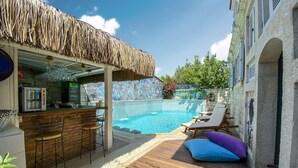 A poolside area with a bar, lounge chairs, and a thatched roof. - Provence Mansion Alacati (Cesme)