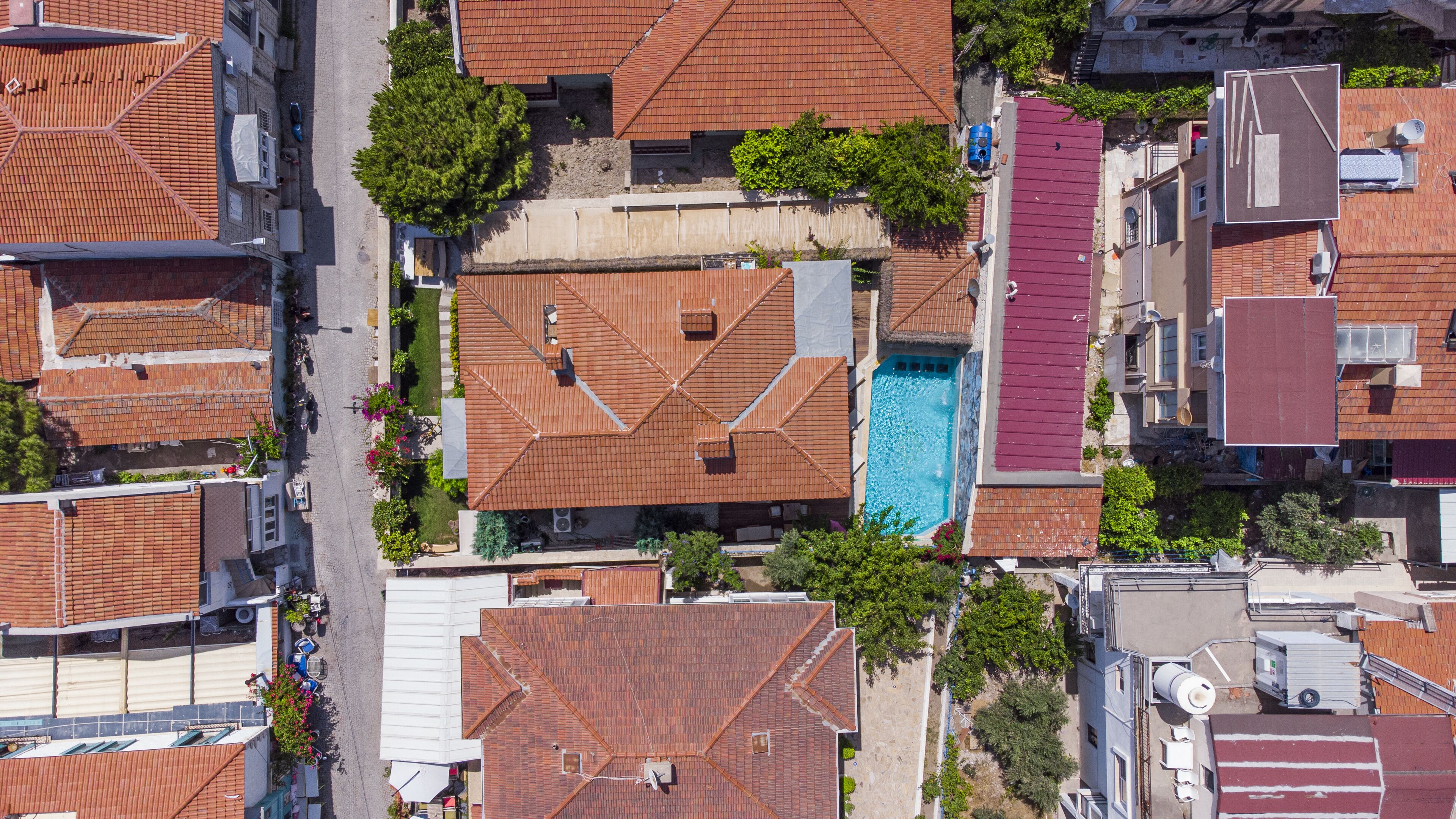 An aerial view of a residential area with multiple houses, a swimming pool, and a street.