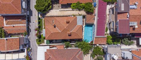 An aerial view of a residential area with multiple houses, a swimming pool, and a street.