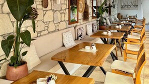 A restaurant with stone walls, wooden tables, and hanging wicker lamps. - Provence Mansion Alacati (Cesme)