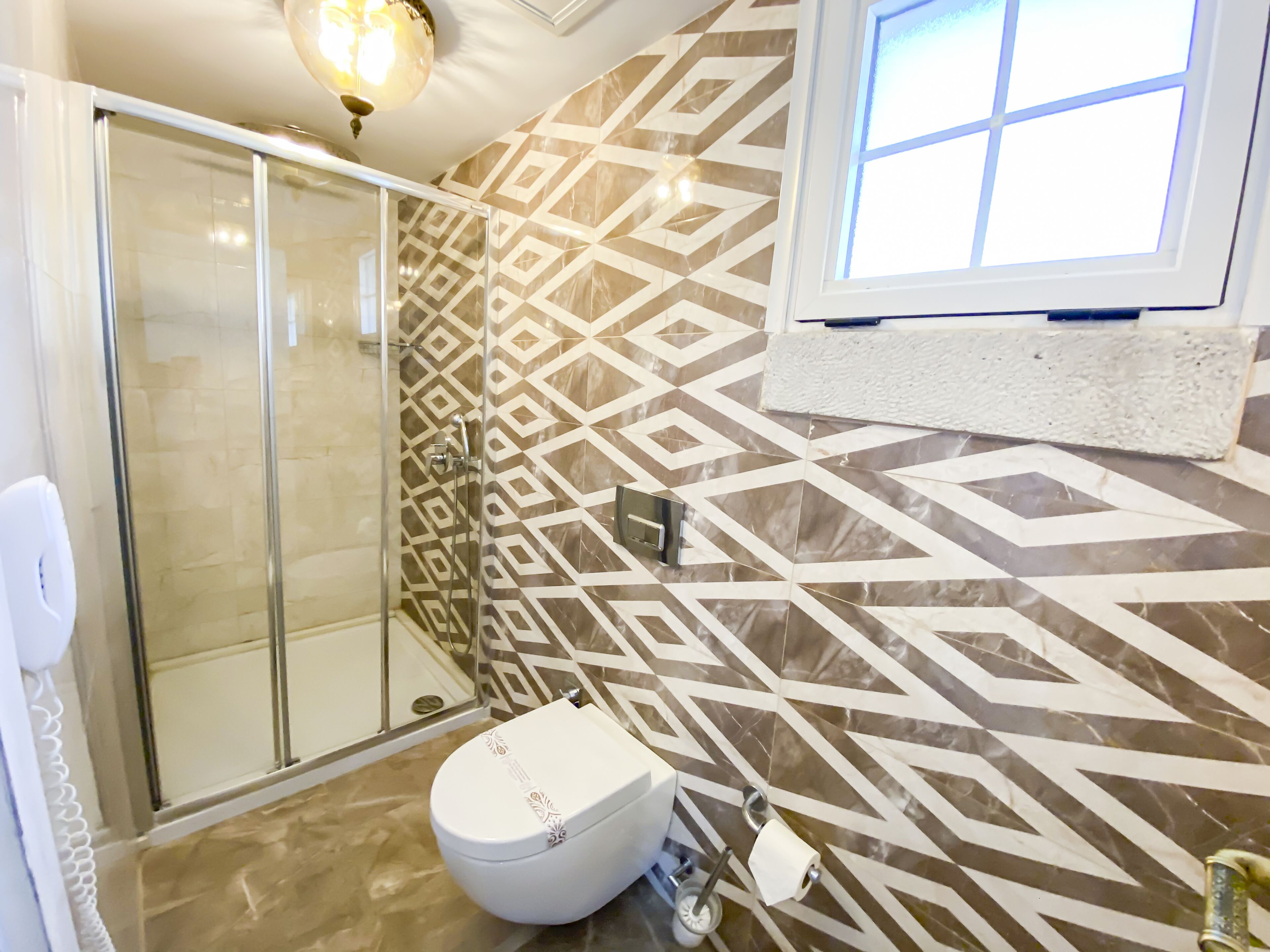 A bathroom with a shower, toilet, and patterned walls.