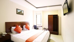A hotel room with a large bed, a desk, a chair, a TV, and a wardrobe. - Hyper Inn (Bandung)