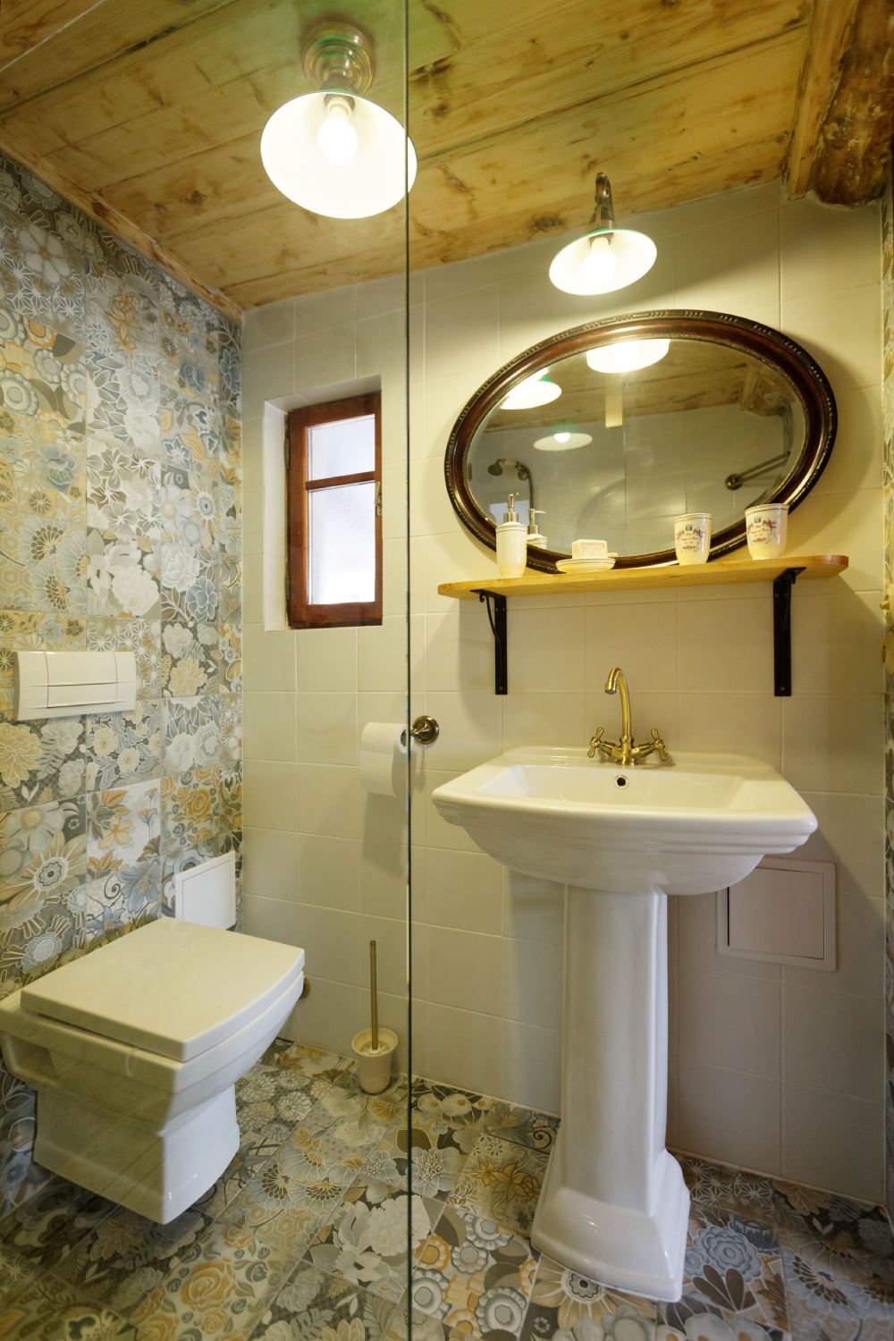 A bathroom with a toilet, a sink with a mirror, and patterned tiles on the walls and floor.