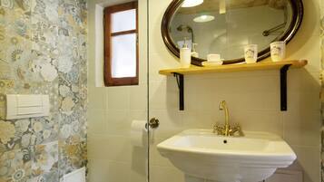 A bathroom with a toilet, a sink with a mirror, and patterned tiles on the walls and floor.