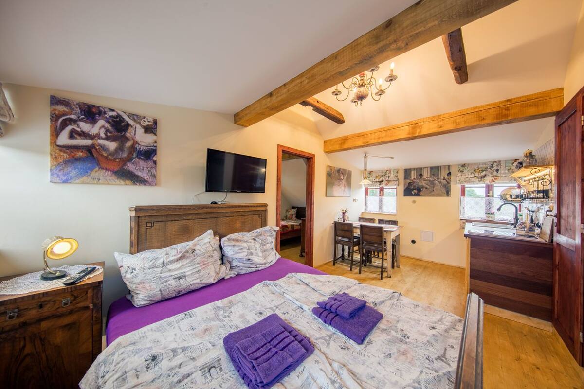 Quarto com cama, escrivaninha e área de refeições.