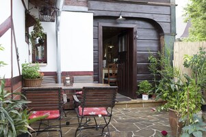 Um pátio com mesa, cadeiras, uma porta de madeira e plantas em vasos.
