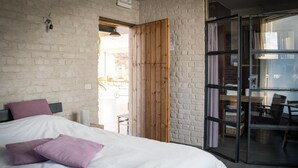 Un dormitorio con una cama grande, una puerta de madera y un ventanal corredero que da a un balcón.