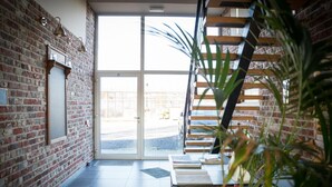Un interior moderno con paredes de ladrillo visto, una escalera y un amplio ventanal hacia el exterior.
