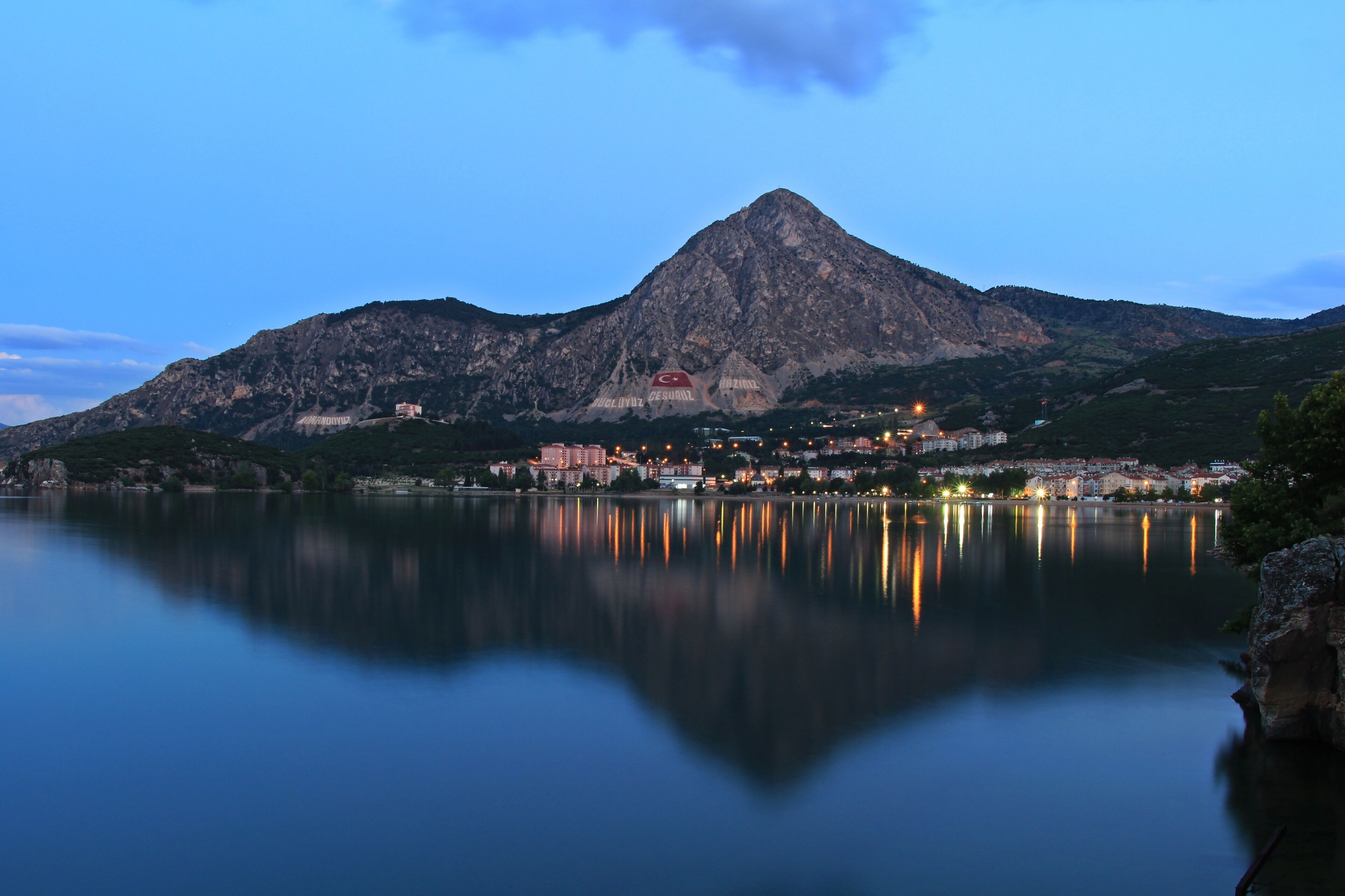 Una montaña reflejada en aguas tranquilas, rodeada de edificios.