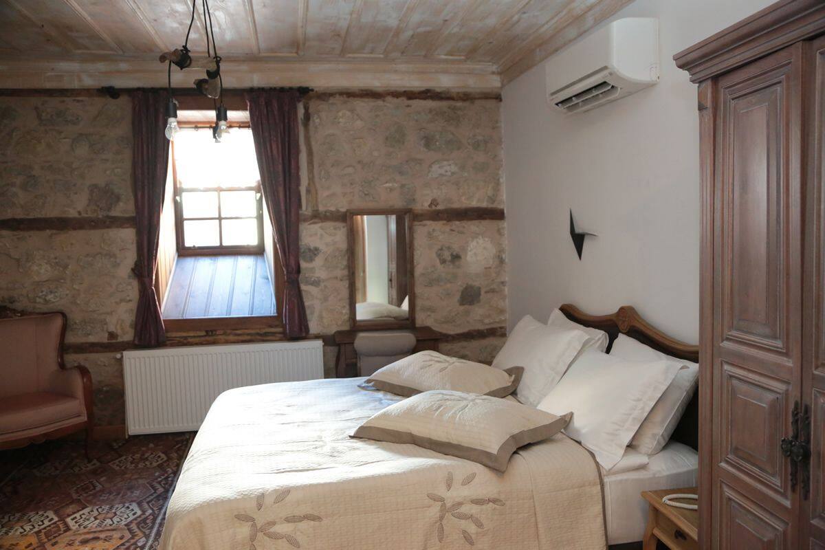 A bedroom with a bed, a chair, a mirror, and a wardrobe.