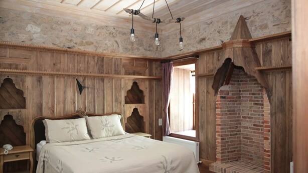 Een rustieke kamer met een houten bed, een metselstenen openhaard en een stenen muur.