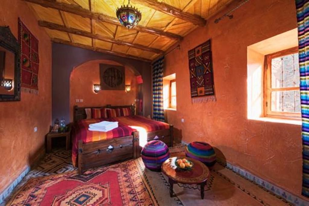 A traditional room with a wooden bed, colorful rugs, and a unique ceiling design.