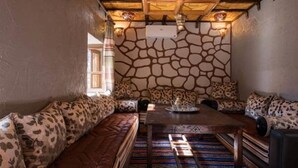 Une pièce chaleureuse avec un mur en pierre, un plafond en bois et un tapis à motifs.