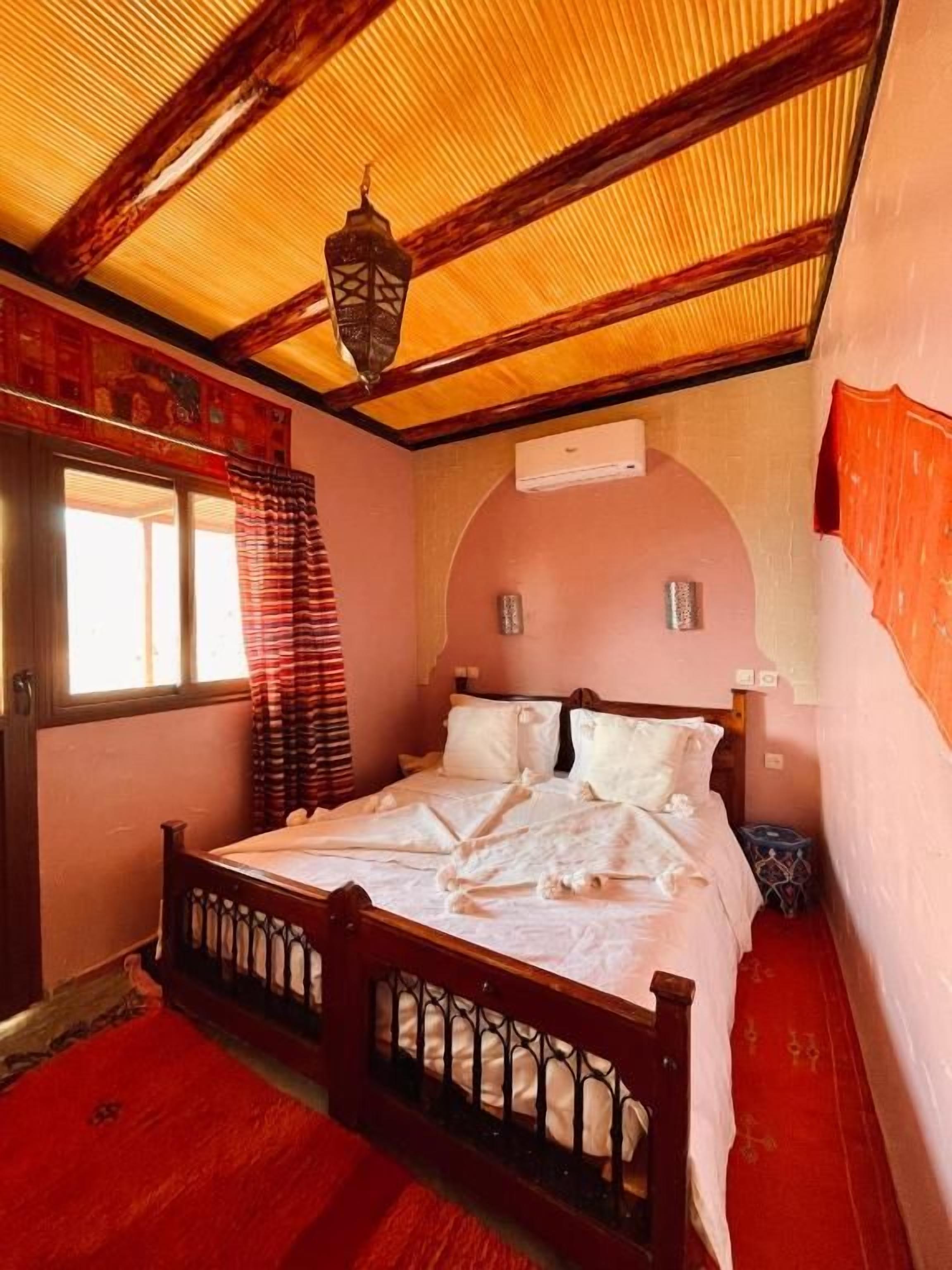 Een slaapkamer met een houten bed, een rood tapijt en een schuine kap.