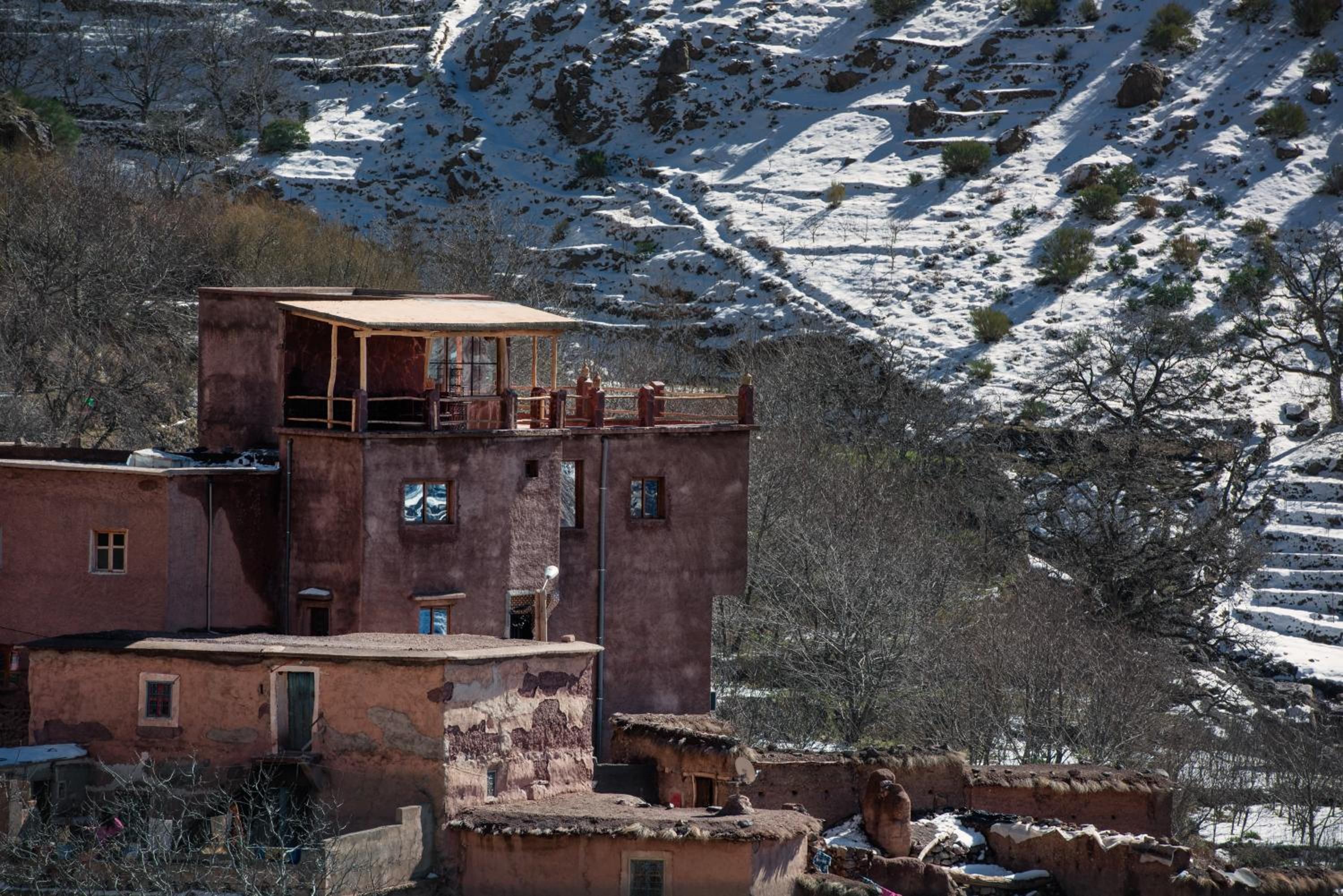 Un bâtiment traditionnel doté d’un balcon, de nombreuses fenêtres et surplombant un paysage montagneux.