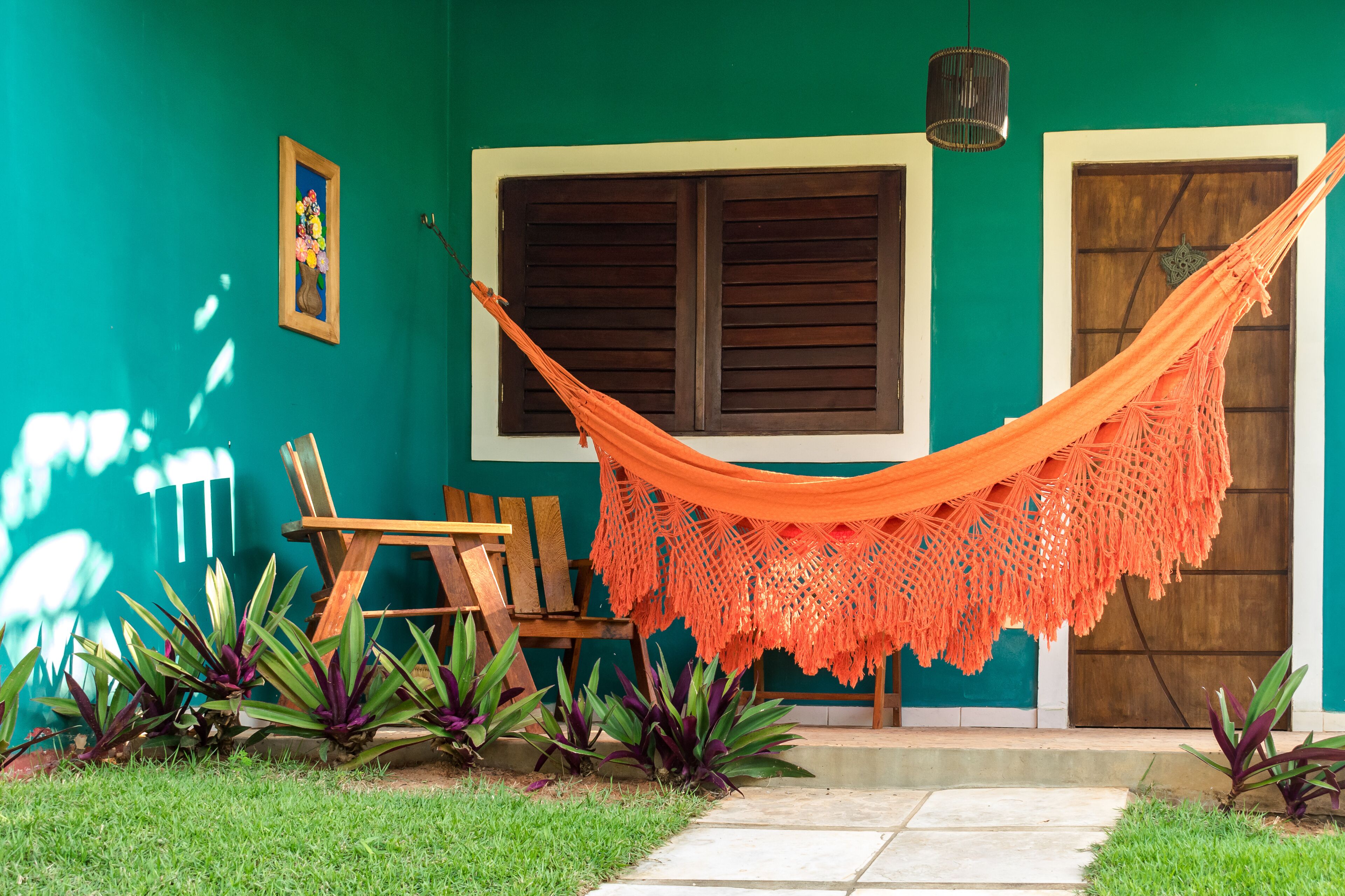 A hammock tied between two wooden doors, a wooden bench, and a small table with a chair.
