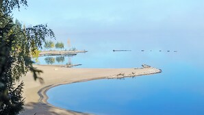 Une plage avec une eau d’un bleu limpide, un rivage sablonneux et une jetée qui s’avance dans l’eau.