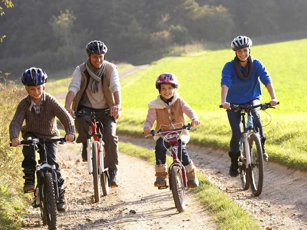 A group of people riding bicycles on a dirt path surrounded by greenery.