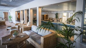 Un vaste espace intérieur aménagé avec des meubles en osier, une piscine et de grandes fenêtres.