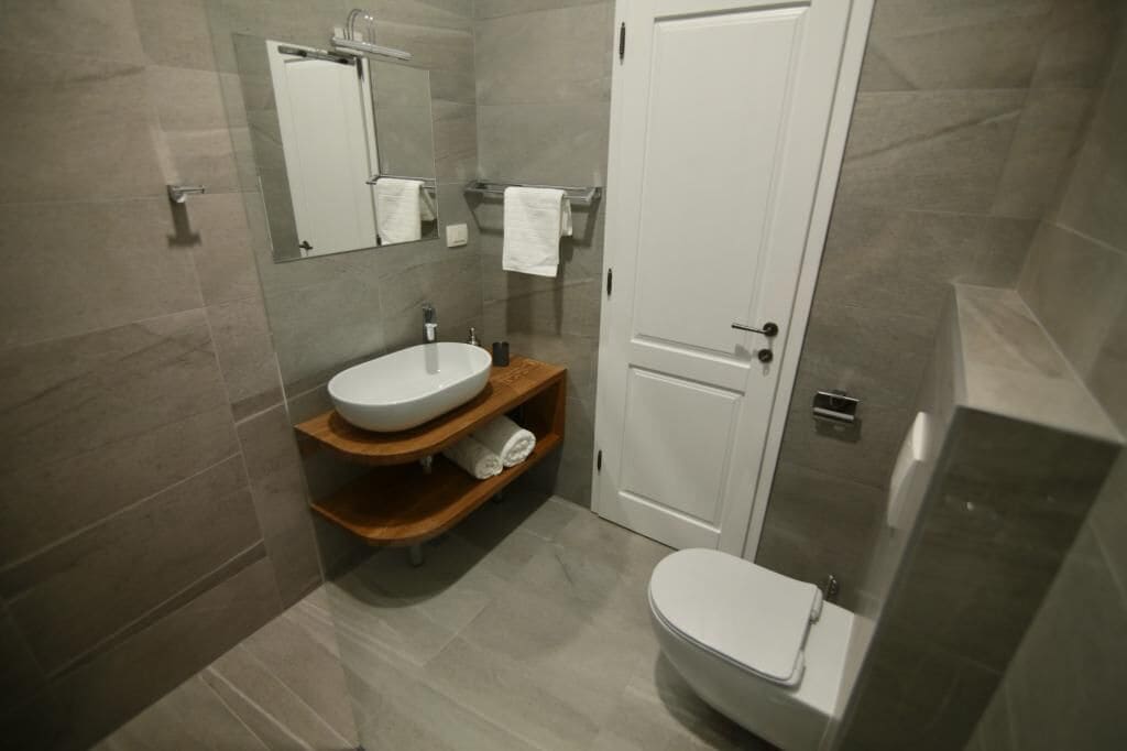 A modern bathroom with a white sink, mirror, and toilet.