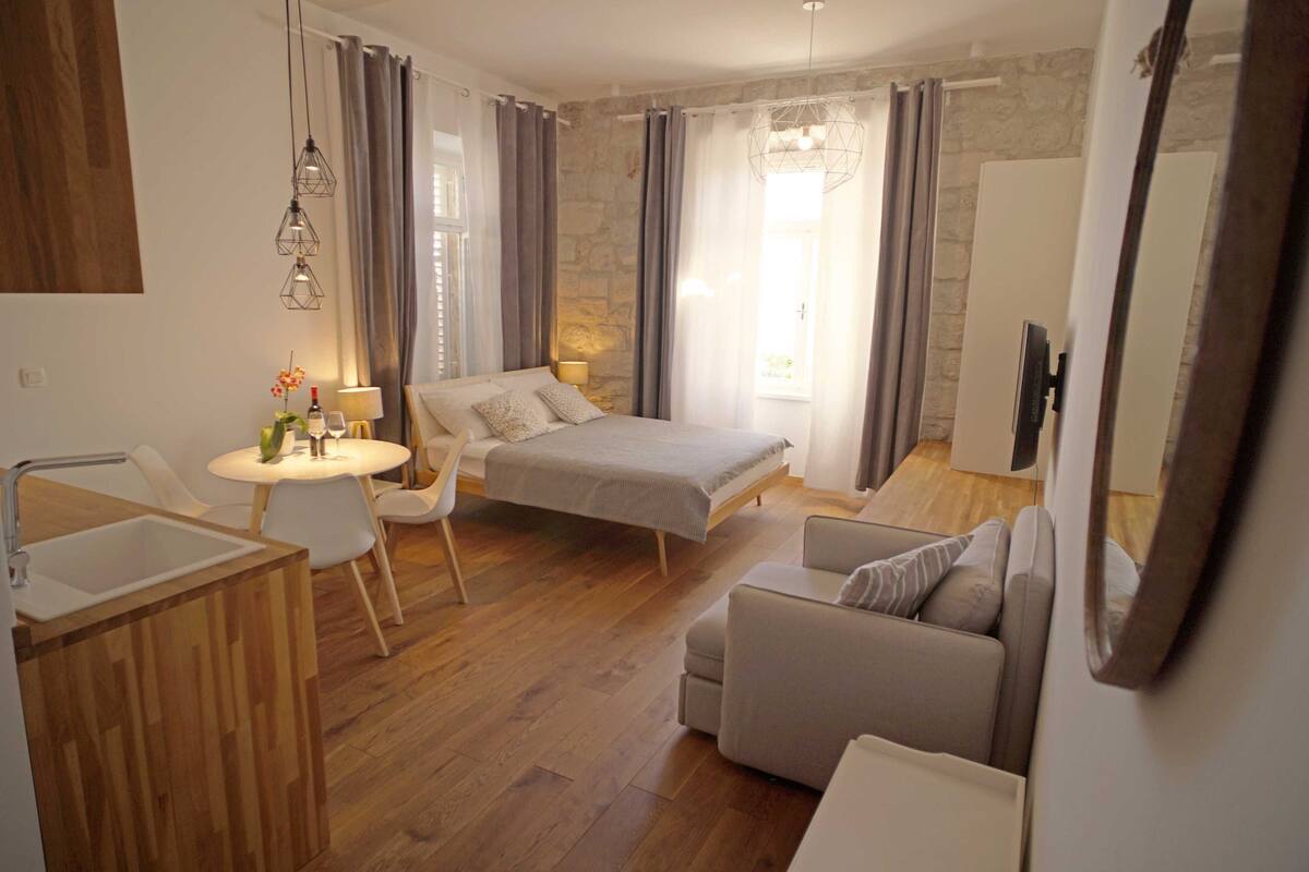 Een moderne slaapkamer met een bed, nachtkastje en een zithoek met een bank en fauteuils.