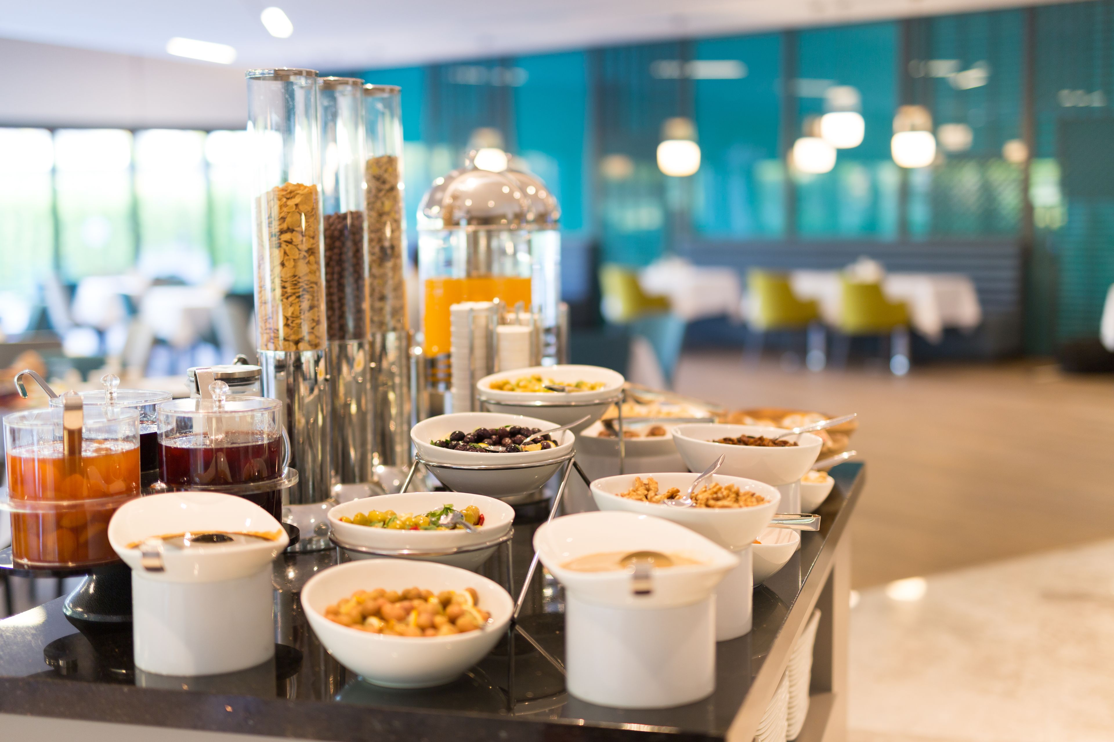 Un bufé con diversos alimentos y bebidas, que incluye tazones de cereal, frutas y una estación de café.