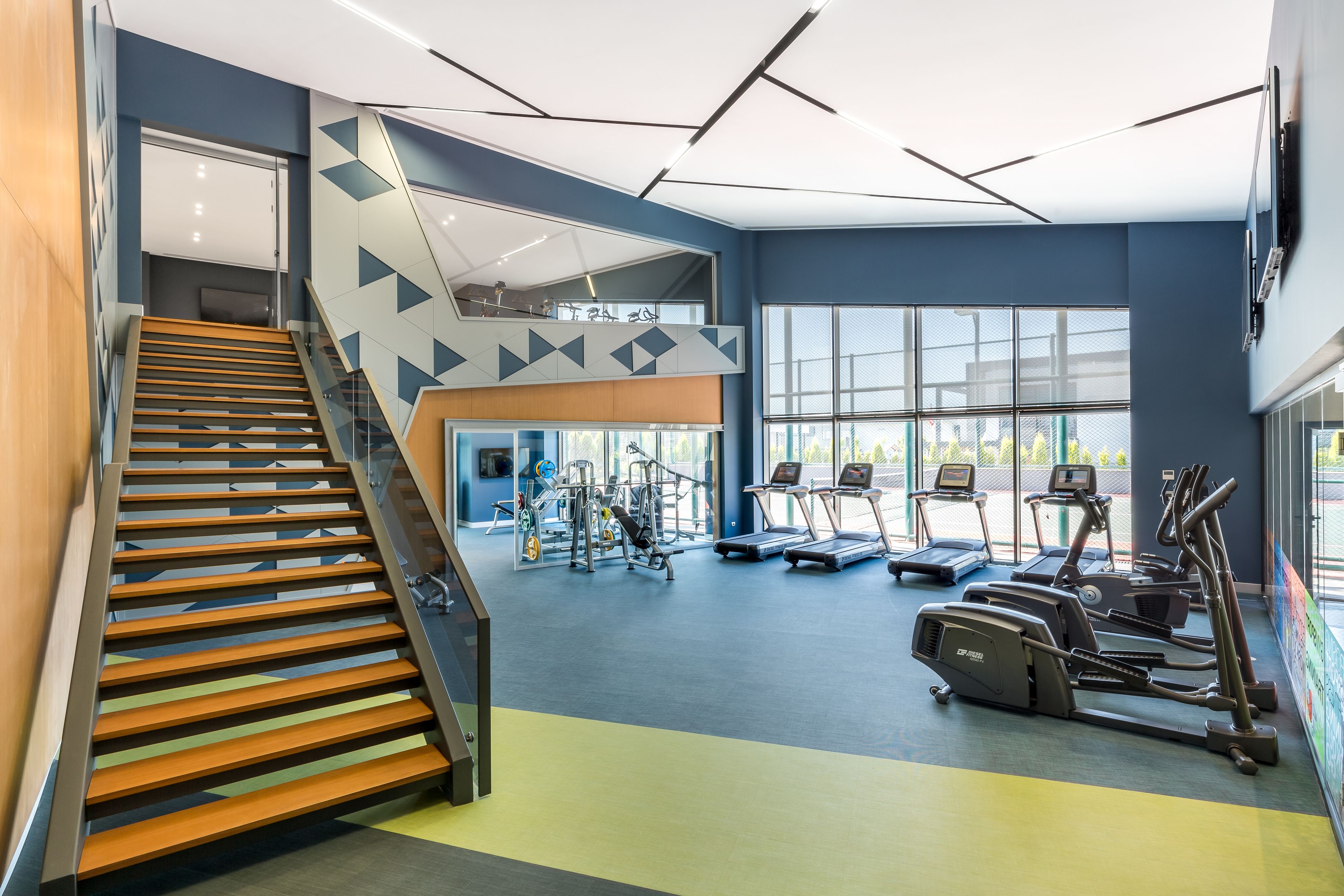 A gym with a staircase, treadmills, and weight machines.