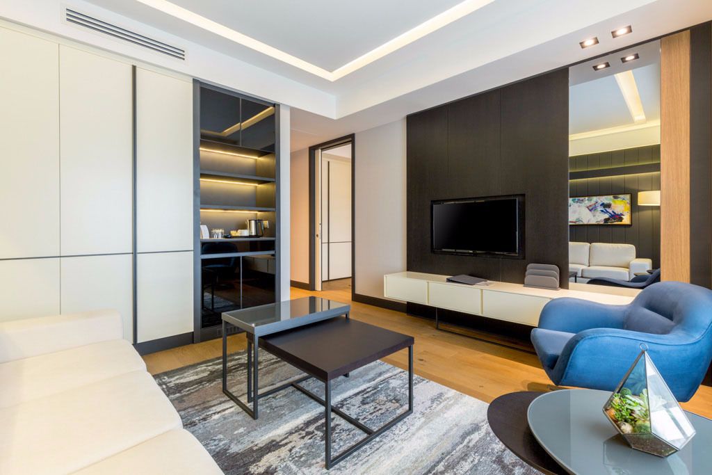 A modern living room with a sofa, a coffee table, a TV, and a blue armchair.