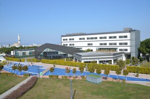 A modern building with a glass facade, a swimming pool, and a mosque in the background. - The Fortyfive Business Hotel & Spa (Manisa)