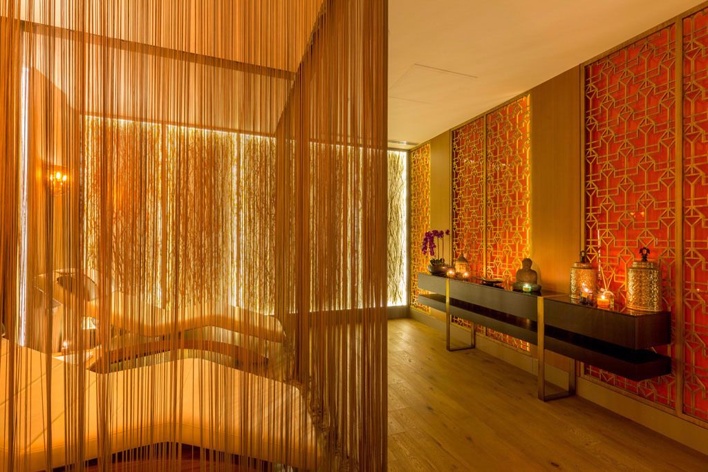 A modern interior with a wooden slatted partition, a bench, and a decorative wall with geometric patterns.