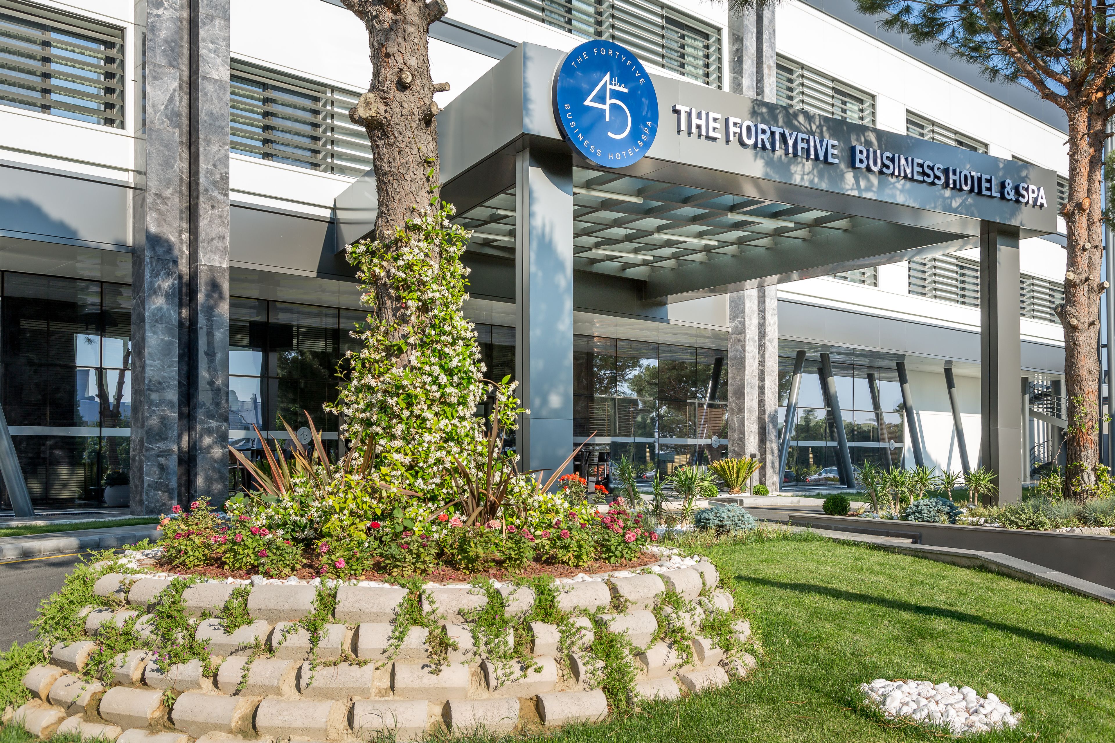 The FortyFive Business Hotel & Spa with a modern facade, large windows, and a landscaped garden area.