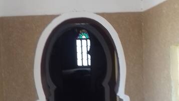 A hallway with a white and orange archway leading to a dark room.