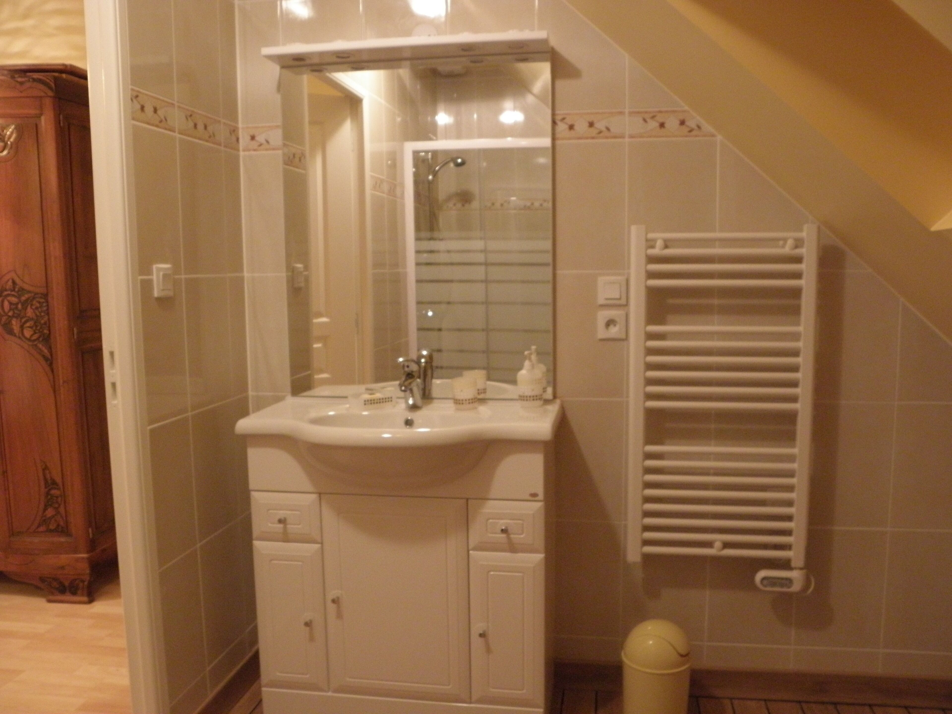 Une salle de bain avec un lavabo blanc, un miroir et un porte-serviettes.