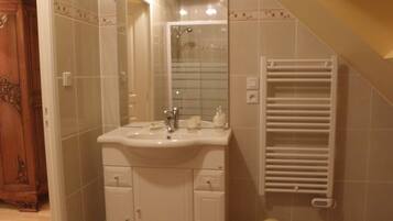 Une salle de bain avec un lavabo blanc, un miroir et un porte-serviettes.