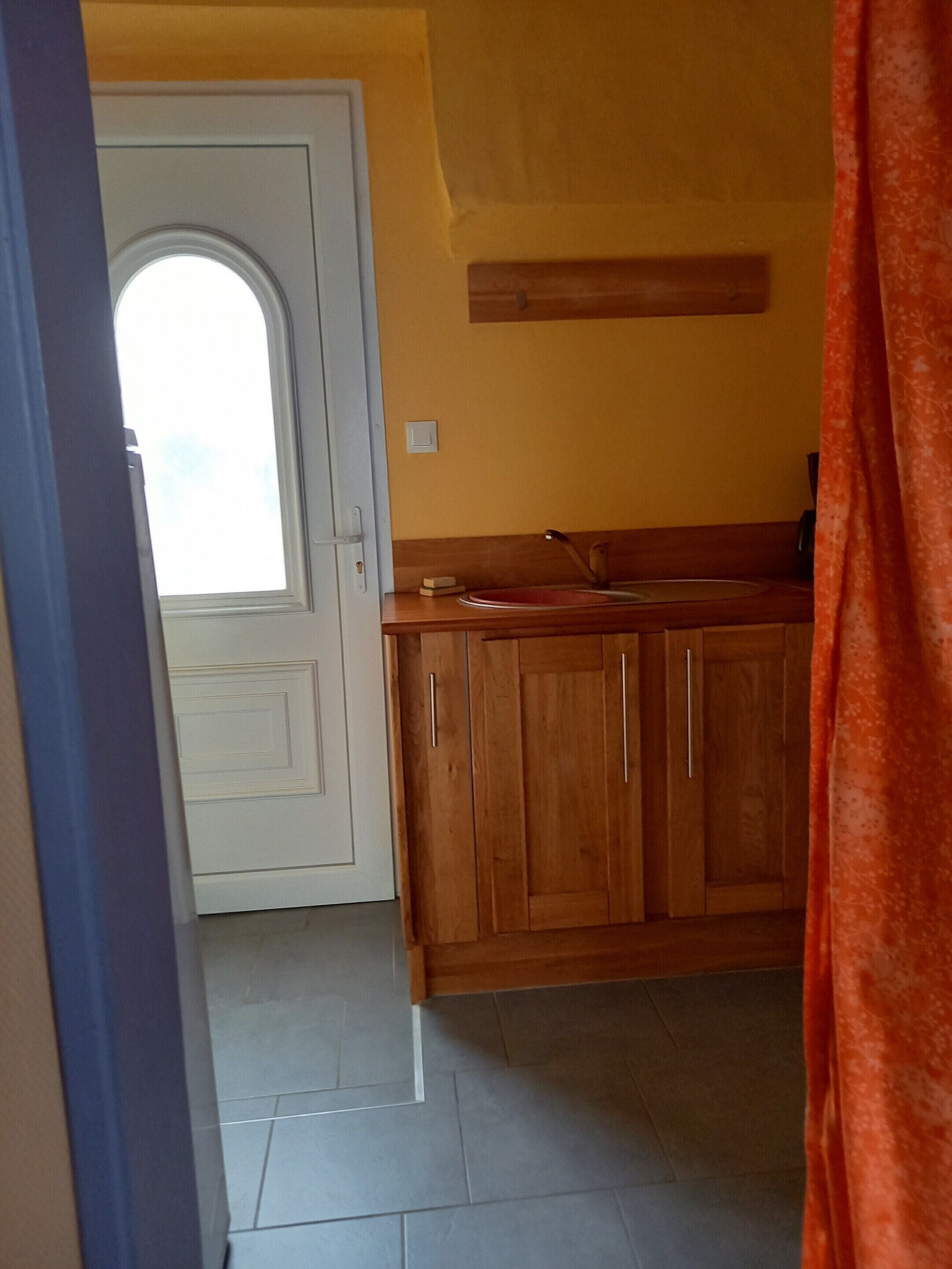Une cuisine avec des meubles de rangement en bois, une porte blanche et une fenêtre.