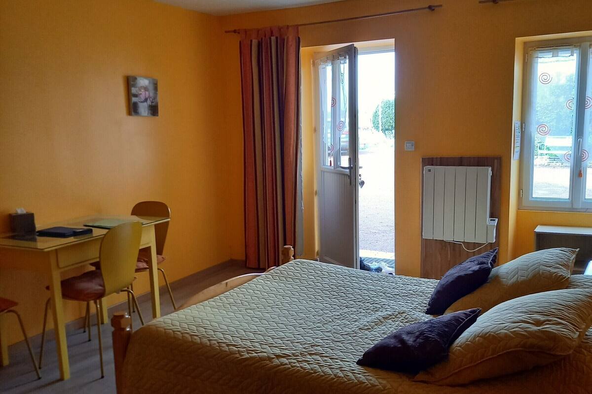 A bedroom with a bed, a desk, a chair, and a window.