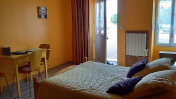 A bedroom with a bed, a desk, a chair, and a window.