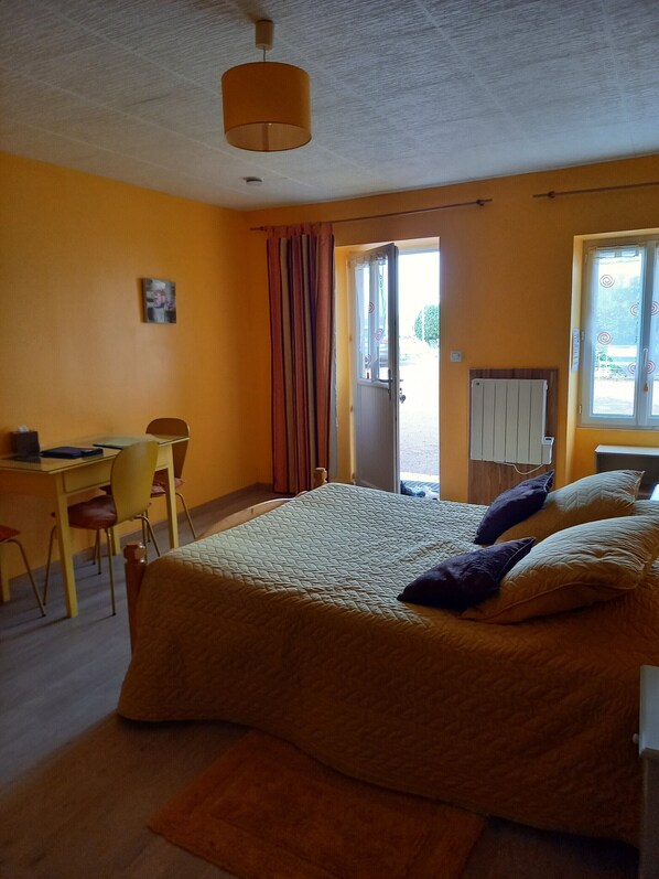 Un dormitorio con cama, escritorio, silla y ventana.